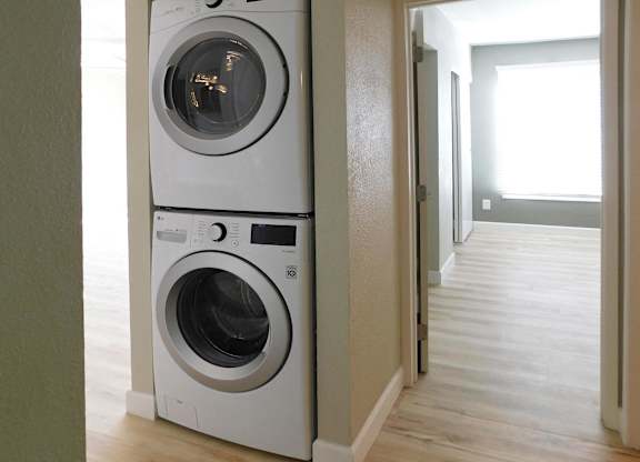 Two white front loading washing machines in a laundry room.