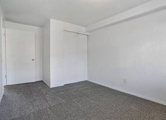 A room with white walls and a grey carpet.