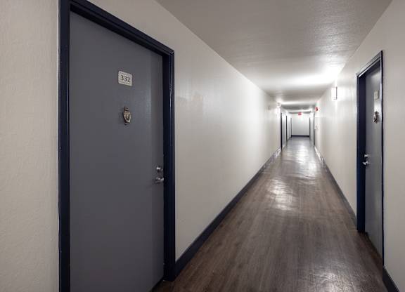 A long hallway with doors on either side and a sign on the wall.