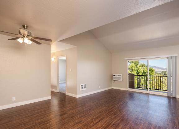 A room with a ceiling fan and sliding glass doors.