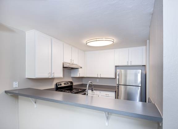 A modern kitchen with stainless steel appliances and white cabinets.