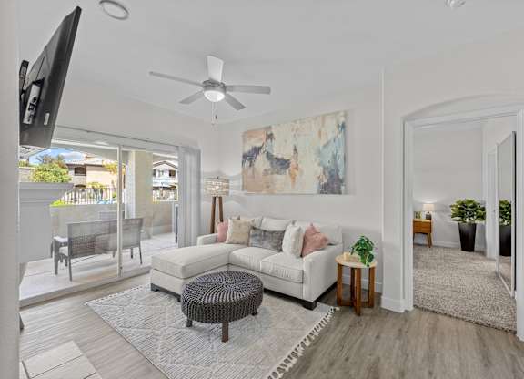 A living room with a white couch and a painting on the wall.