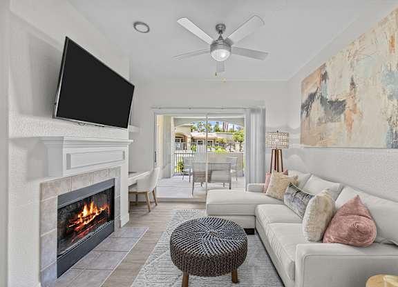 A living room with a fireplace and a television mounted above it.