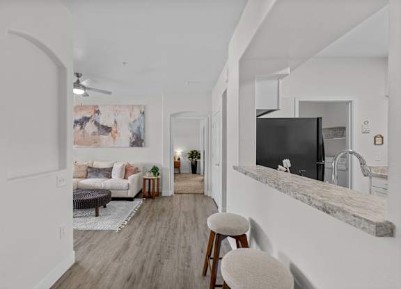 A kitchen area with a bar stool and a counter.