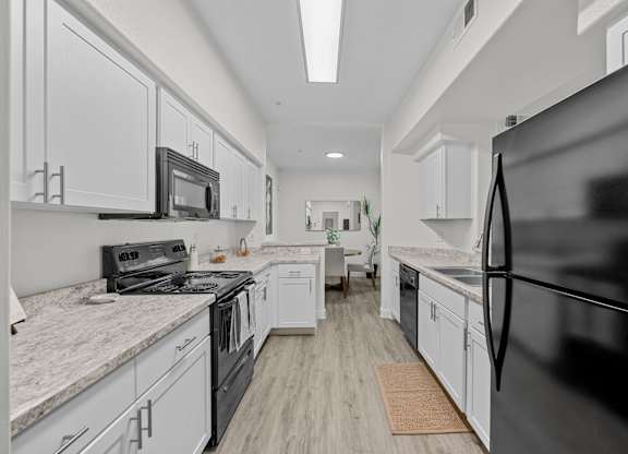 A modern kitchen with black appliances and white cabinets.
