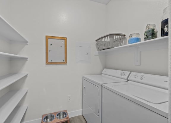 a white laundry room with a washer and dryer and shelves