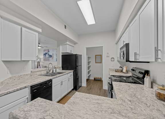 A kitchen with white cabinets and a marble countertop.