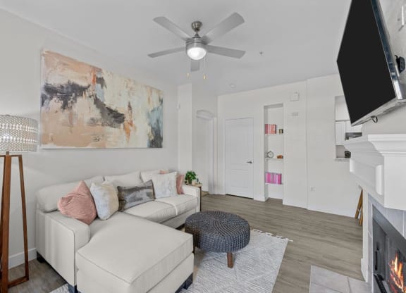 a living room with a white couch and a ceiling fan