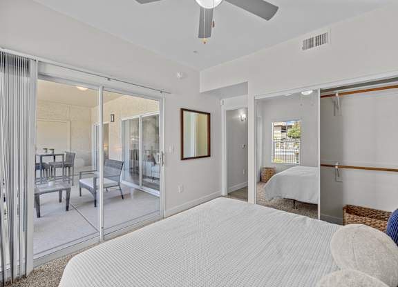 A bedroom with a large bed and a sliding glass door leading to a balcony.