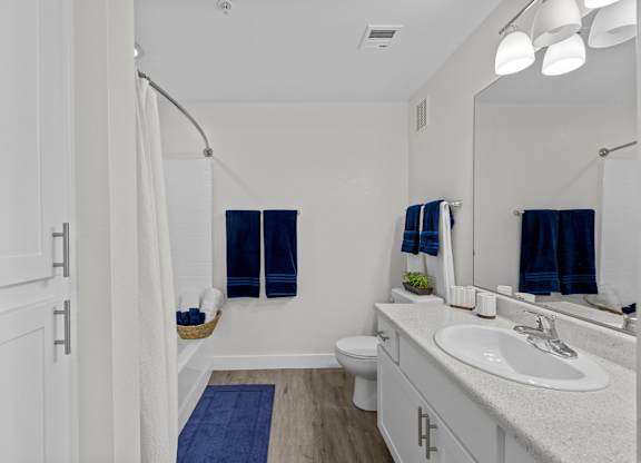 A white bathroom with a blue rug on the floor.