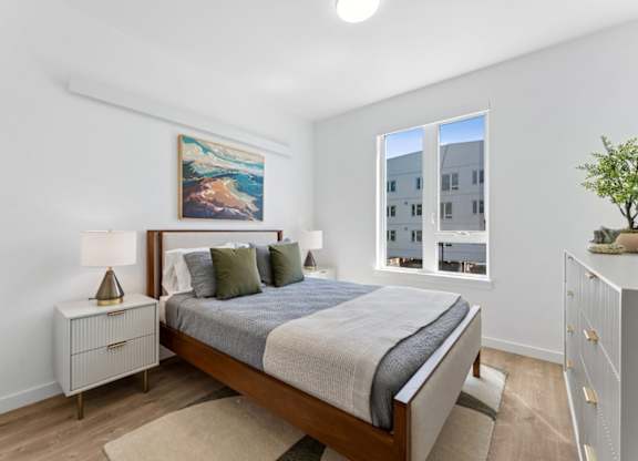 A bedroom with a large bed, a nightstand, and a painting on the wall.