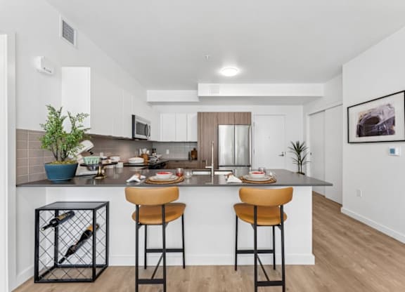 A kitchen with a bar stool and a potted plant.