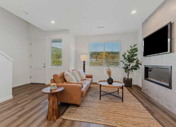 A living room with a brown couch, a coffee table, and a flat screen TV mounted on the wall.