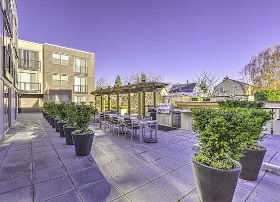 A patio with tables and chairs surrounded by potted plants.