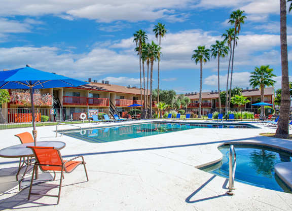 A pool surrounded by palm trees and chairs.