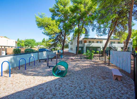 A playground with a green slide and a sandy area.