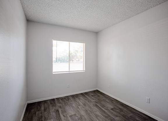 A room with a window and wooden flooring.