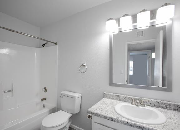 A white bathroom with a toilet, sink, and mirror.