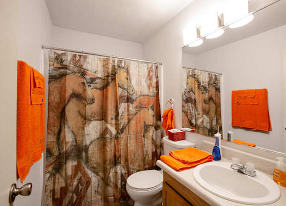 A bathroom with a horse print shower curtain.