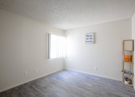 A room with a wooden floor and a picture frame on the wall.