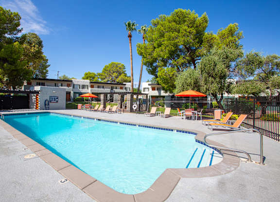 A large swimming pool surrounded by trees and chairs.