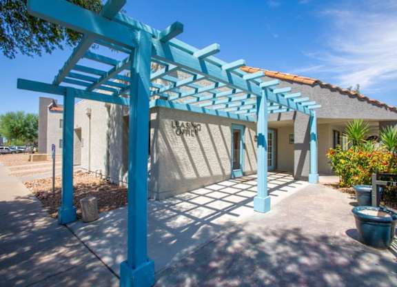 A blue pergola is in front of a building with the words "Leasing Office" on it.