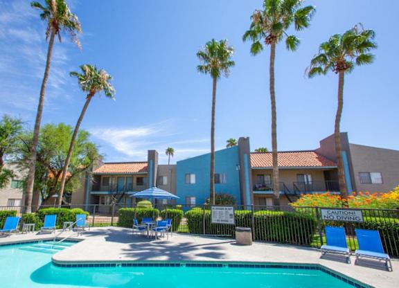 A pool surrounded by palm trees and a caution sign.