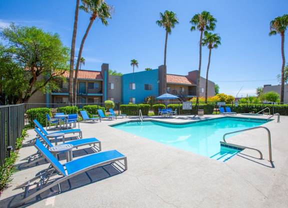 A pool surrounded by palm trees and sun loungers.