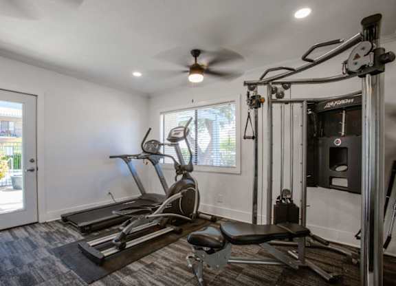 A home gym with a treadmill, elliptical trainer, and other exercise equipment.