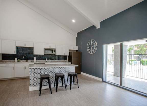 A kitchen with a bar stool and a clock on the wall.