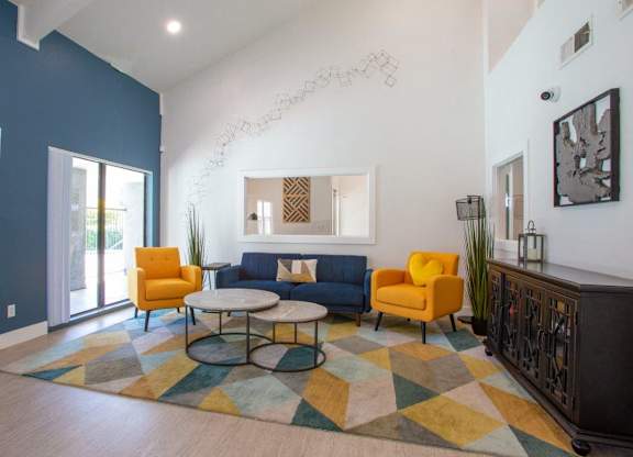 A living room with a blue couch, yellow chairs, and a colorful rug.