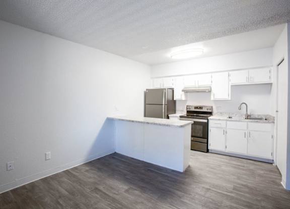 A kitchen with white cabinets and a wooden floor.