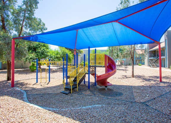 A playground with a blue canopy and a red slide.