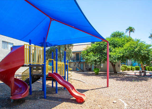 A red slide is in the middle of a playground.