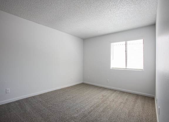 A room with a window and carpeted floor.