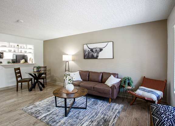 A living room with a brown couch, a coffee table, and a painting on the wall.