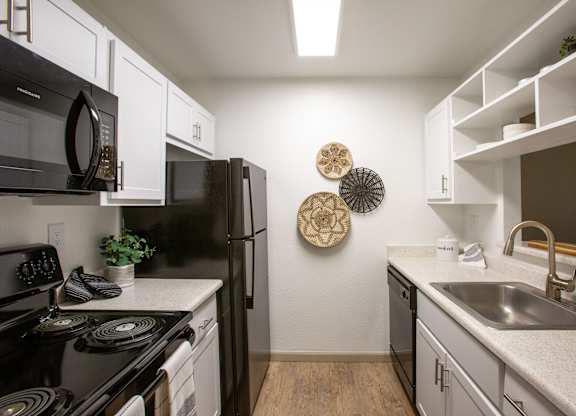 A kitchen with black appliances and white cabinets.