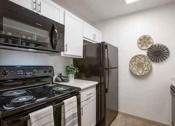A black stove top oven with a white counter top and a black refrigerator in a kitchen.