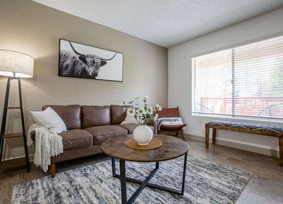 A living room with a brown leather couch, a coffee table, and a painting of a cow on the wall.