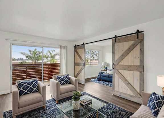 A living room with a glass coffee table and a sliding barn door.