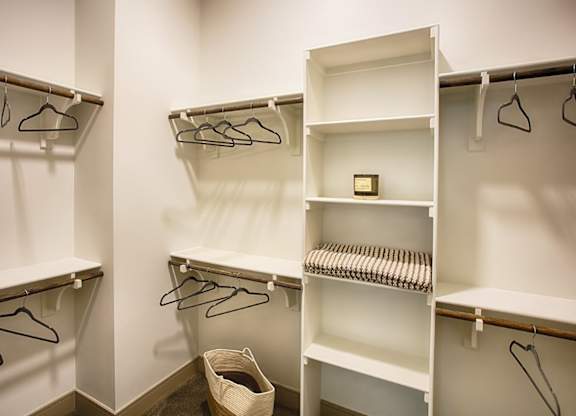 A white closet with clothes hangers and shelves.