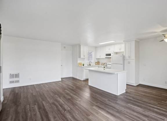 A spacious kitchen with white cabinets and a wooden floor.