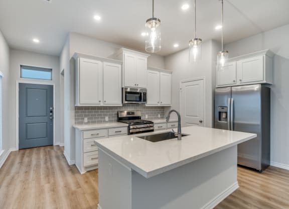 an open kitchen with white cabinets and a marble counter top