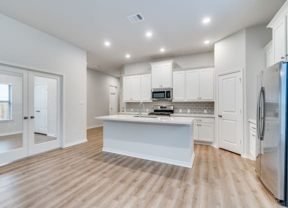 an open kitchen with white cabinets and a white counter top
