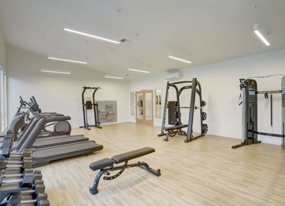 a gym with treadmills and weights in a building with white walls