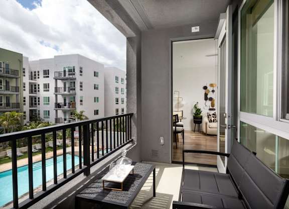 A balcony with a black couch and a pool in the background.