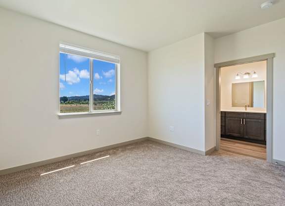 A room with a large window and a carpeted floor.