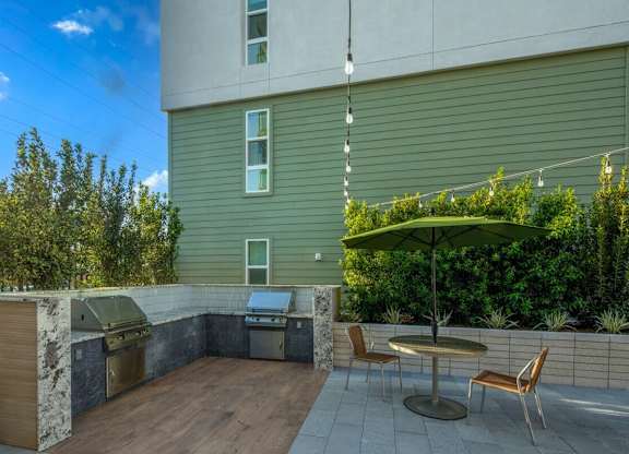 A patio with a table and chairs and a grill.