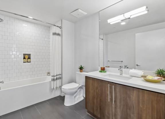 A white bathroom with a wooden cabinet and a white tub.