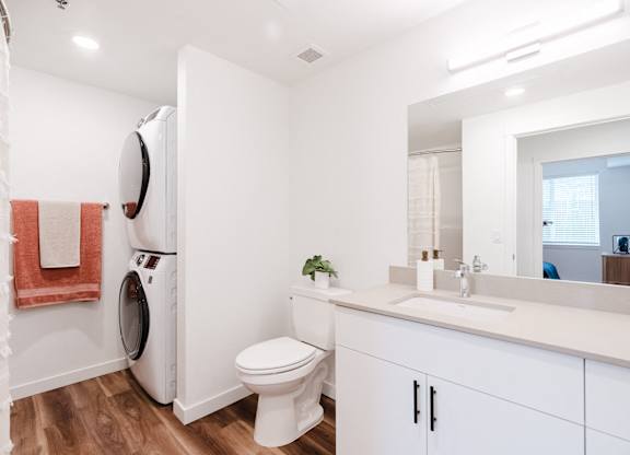 A white bathroom with a toilet, sink, and mirror.
